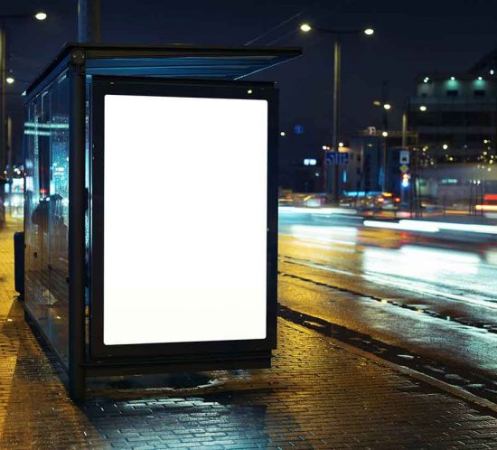 Beleuchtetes Citylight Poster an einer Bushaltestelle bei Nacht